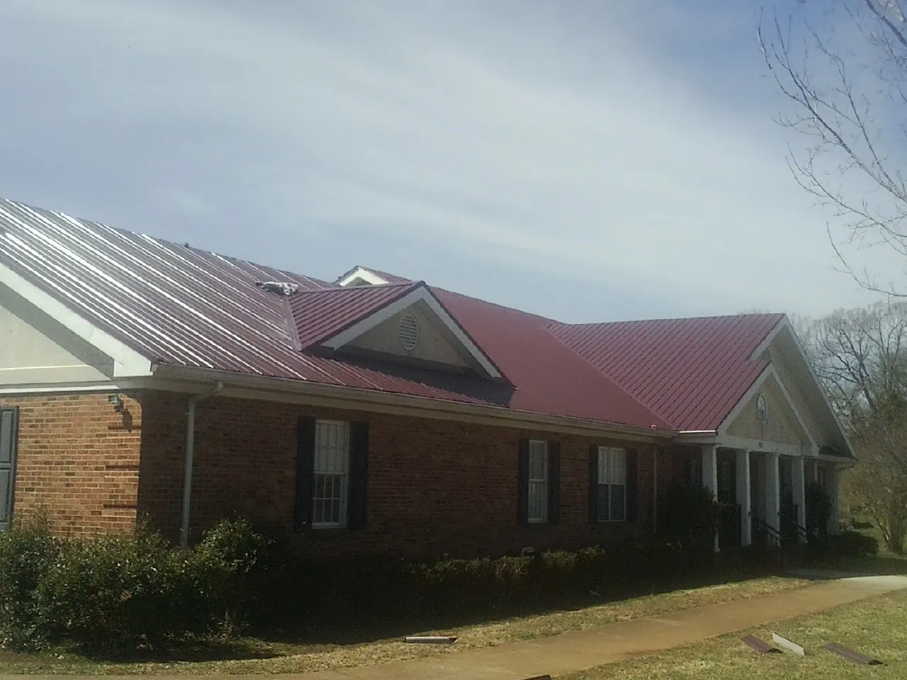 Red metal roof with gabled entries on a long brick building in Drake