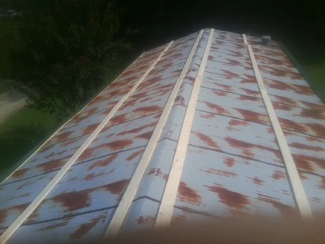 Rusted metal roof panels with new wood purlins before replacement — Storm Damage Roof Repair in Drake by Roofing Brothers