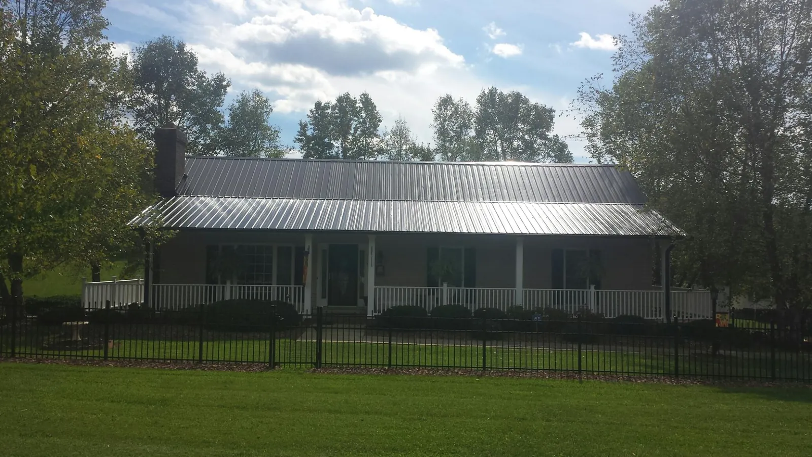 Gray metal roof on a brick ranch with a full width front porch — Gutter Guard Installation work by our crew in Drake
