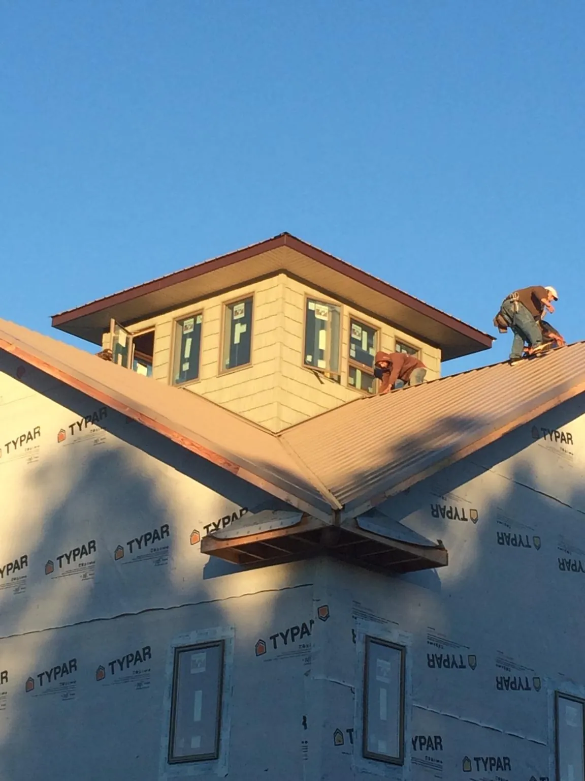 Roofers working around a rooftop cupola on a new metal roof at sunset — Roof Waterproofing in Drake by Roofing Brothers